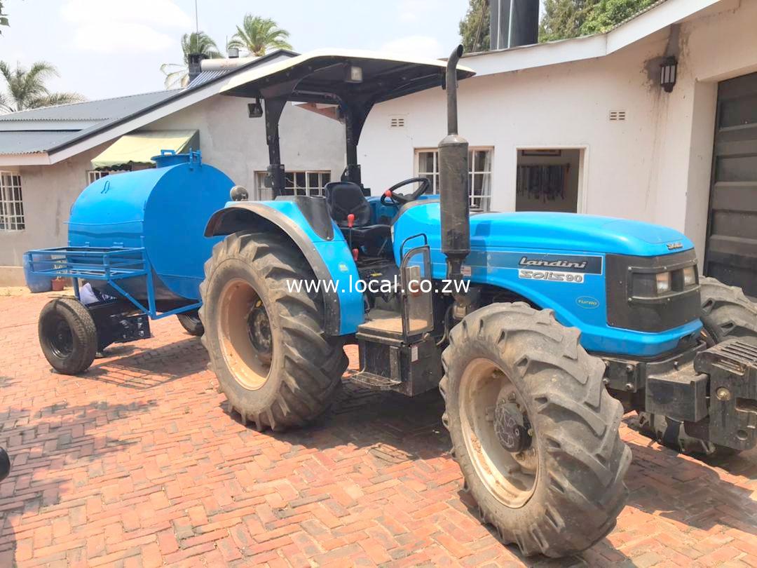 Tractor Hire Harare - Tractor Hire Zimbabwe - Tractor Hire Near Me - Tractor Hire Rates Zimbabwe - Tractor for Rent Harare - Agricultural Equipment Hire in Harare Zimbabwe Blue Tractor pulling a blue trailer at TowTruck24 Zim Workshop in Umwinsdale